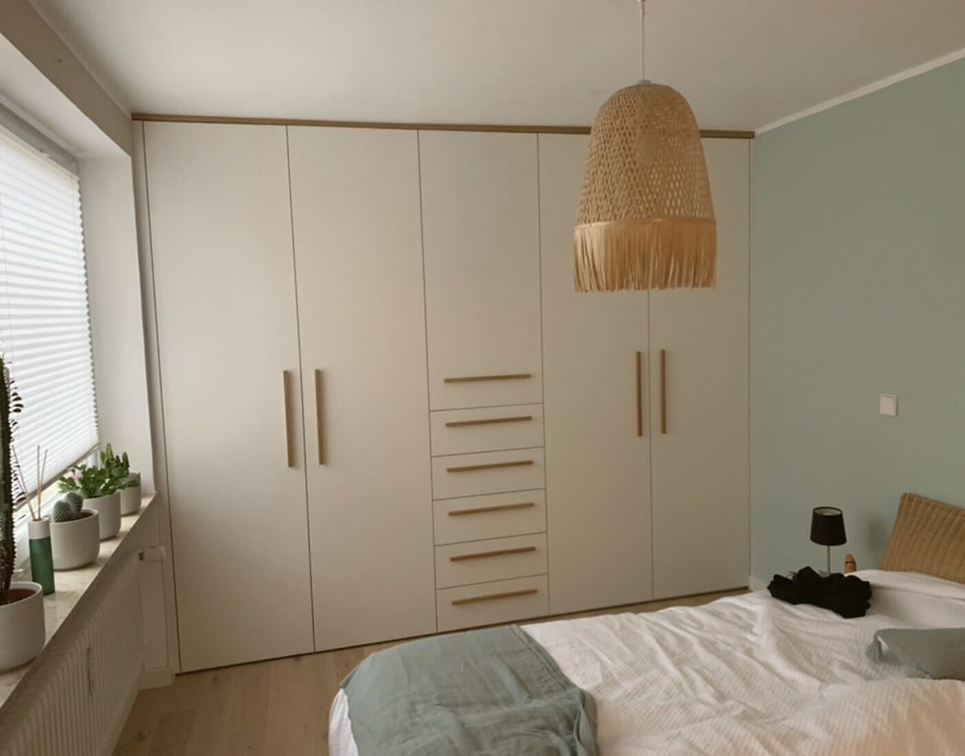 Raumhoher Einbauschrank im Schlafzimmer mit cremefarbenen Fronten und Holzgriffen